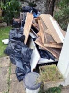 Mixed household and bulky rubbish ready for collection in Tunbridge Wells, including timber boards, black sacks and broken furniture panels
