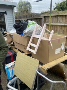 Backyard area filled with cardboard boxes, black bags and household items requiring bulk waste removal