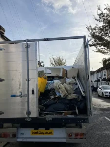 JunkGuy rubbish removal truck loaded with household and construction waste in Croydon residential street