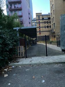 Residential estate entrance after rubbish clearance — clear pathway and iron gate, Elephant and Castle SE1