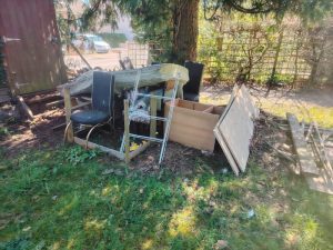 Mixed household rubbish pile with chair, wood panels and furniture pieces awaiting removal in Sevenoaks