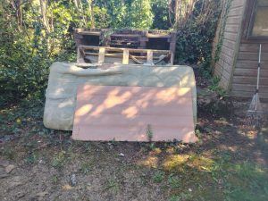 Discarded mattress, wooden board and pallet pieces stacked outdoors for rubbish removal in Sevenoaks